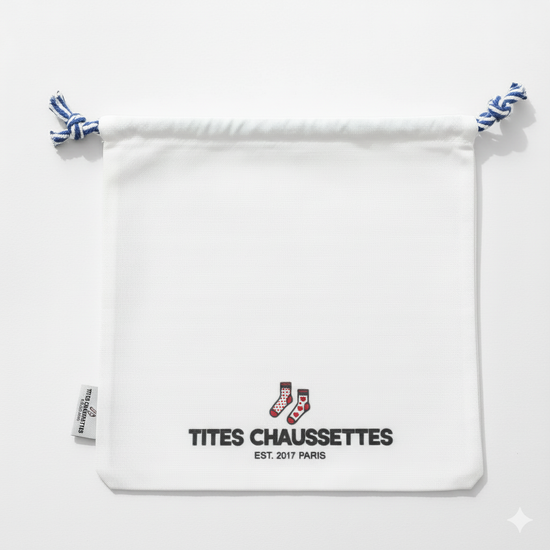 Pochon coton pour ranges ses Tites Chaussettes. Fond blanc, imprimé chaussettes à motifs bleu/rouge. Fermeture par lien coulissant blanc/bleu. 