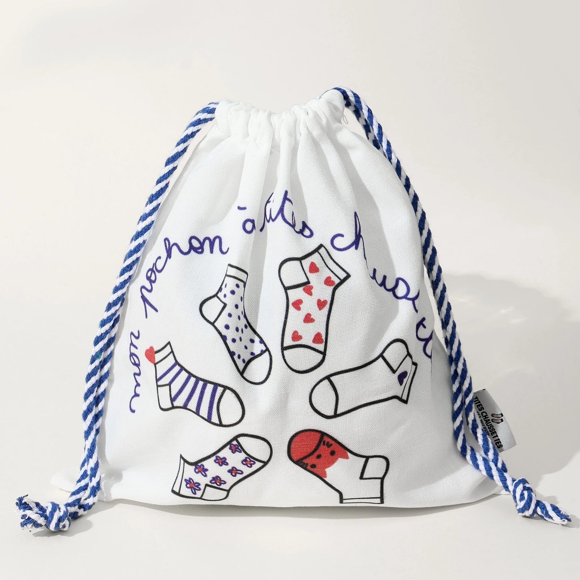 Pochon coton pour ranges ses Tites Chaussettes. Fond blanc, imprimé chaussettes à motifs bleu/rouge. Fermeture par lien coulissant blanc/bleu. 