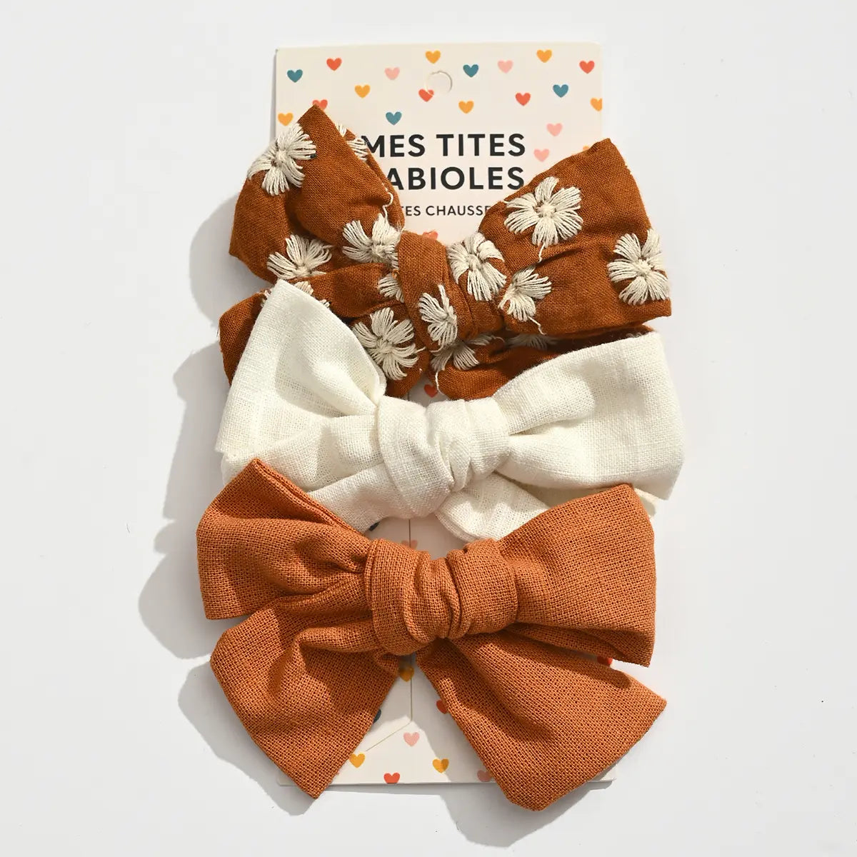 Lot de 3 barrettes pince croco fille avec nœuds en tissu aux tons doux. Accessoires cheveux élégants et confortables pour bébé et enfant.