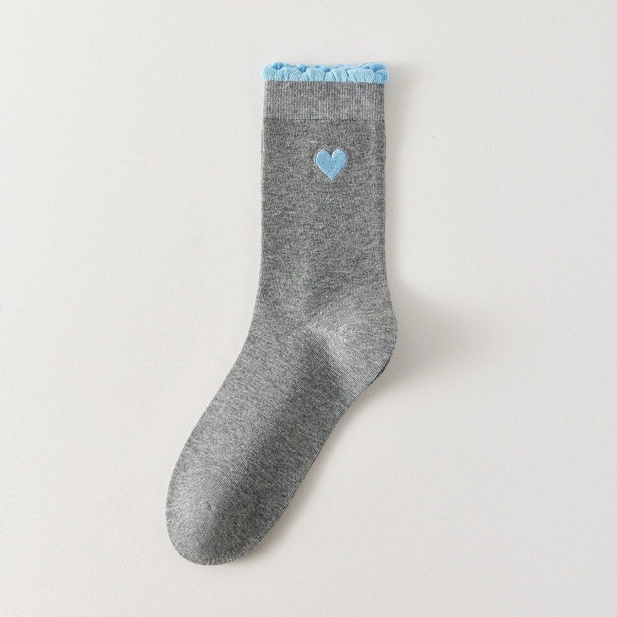 Chaussettes femme montantes avec coeur brodé sur le côté. Haut de tige volanté. Coeur et volant contrastés. 