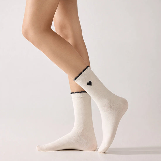 Chaussettes femme montantes avec coeur brodé sur le côté. Haut de tige volanté. Coeur et volant contrastés. 