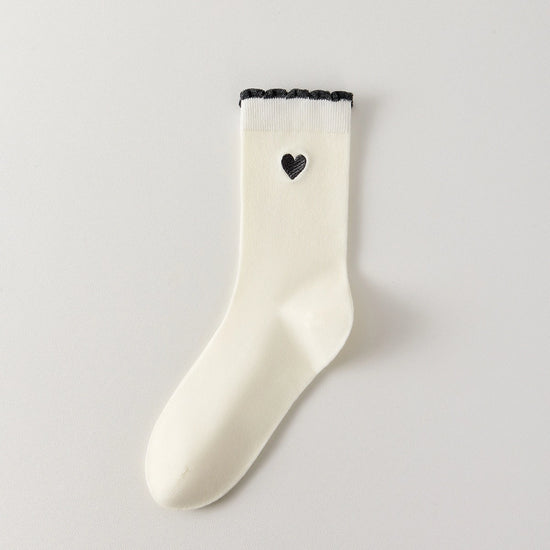 Chaussettes femme montantes avec coeur brodé sur le côté. Haut de tige volanté. Coeur et volant contrastés. 