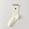 Chaussettes femme montantes avec coeur brodé sur le côté. Haut de tige volanté. Coeur et volant contrastés. 
