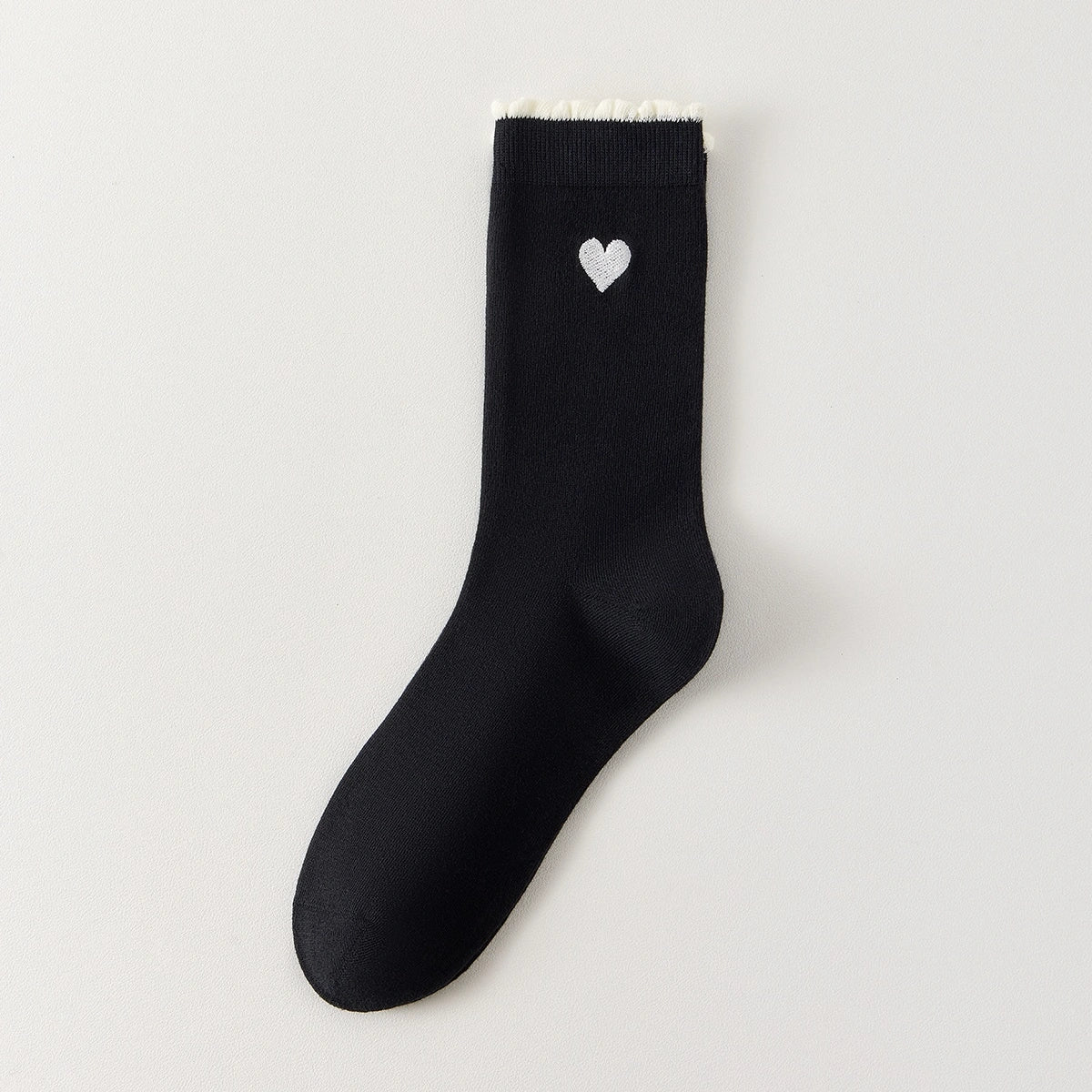 Chaussettes femme montantes avec coeur brodé sur le côté. Haut de tige volanté. Coeur et volant contrastés. 