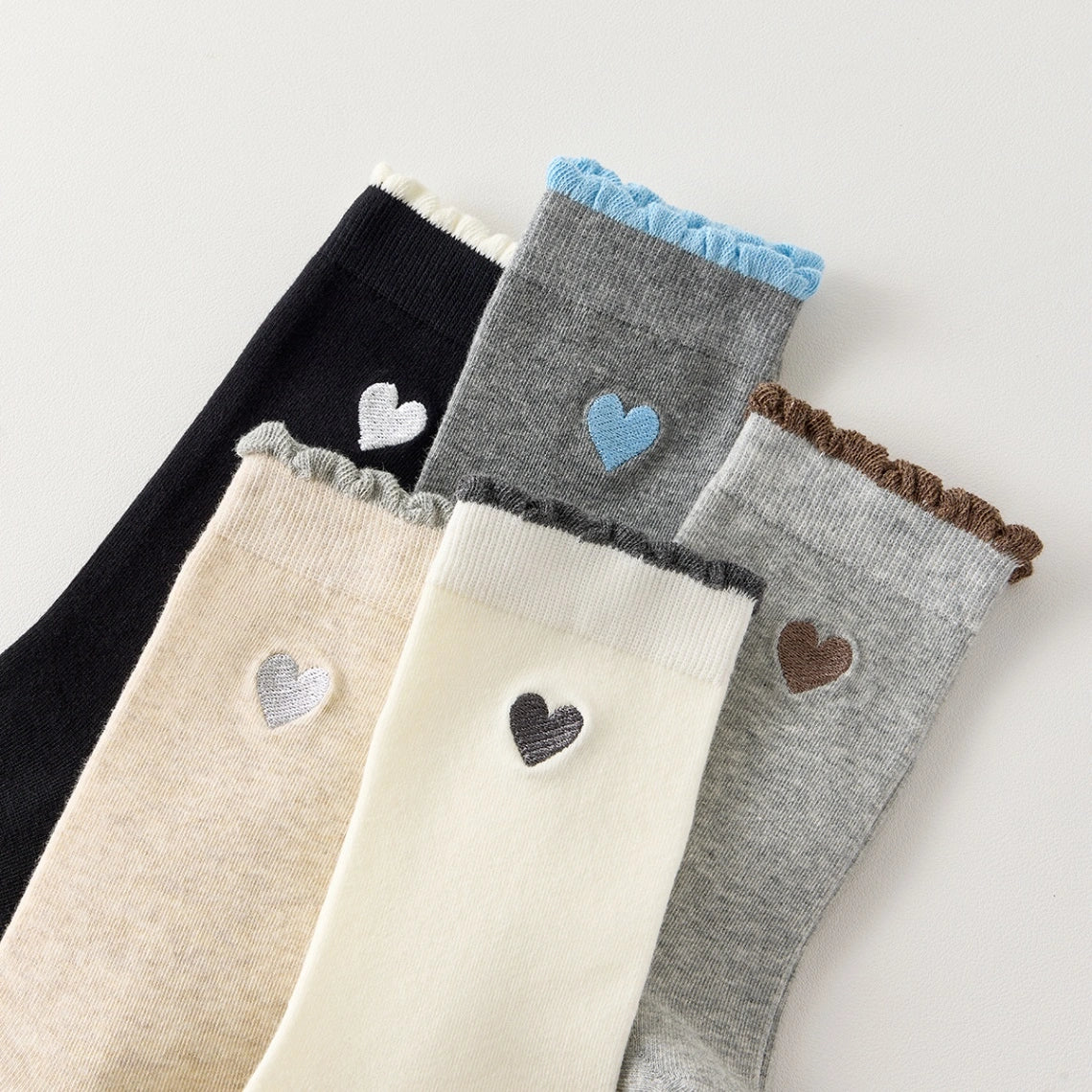 Chaussettes femme montantes avec coeur brodé sur le côté. Haut de tige volanté. Coeur et volant contrastés. 