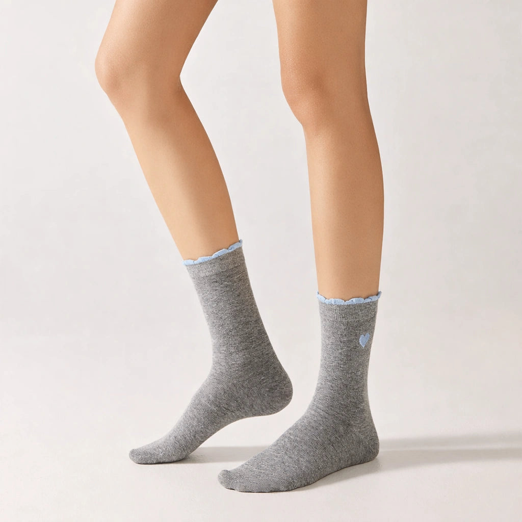 Chaussettes femme montantes avec coeur brodé sur le côté. Haut de tige volanté. Coeur et volant contrastés. 