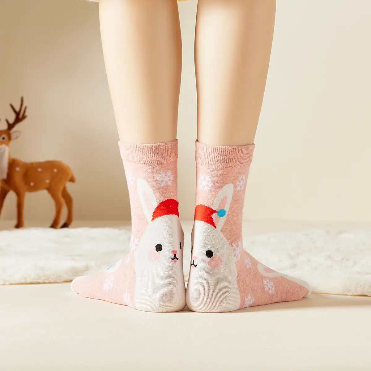 Chaussettes roses de noël motif flocons et tête de lapin portant un bonnet de noël 