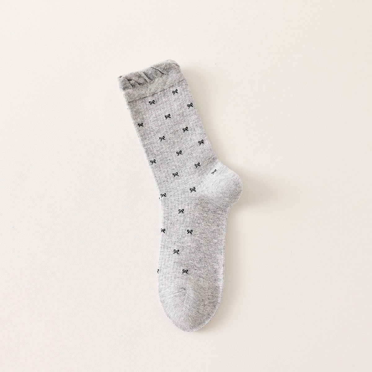 Chaussettes montantes tige côtelée. Motif petit noeud noir. Finition volant sur le haut de tige. Disponibles en blanc, gris chiné clair et noir. 