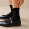 Chaussettes montantes tige côtelée. Motif petit noeud noir. Finition volant sur le haut de tige. Disponibles en blanc, gris chiné clair et noir. 