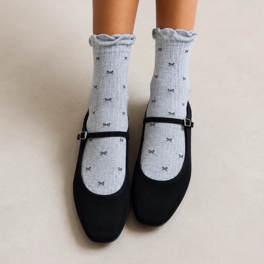 Chaussettes montantes tige côtelée. Motif petit noeud noir. Finition volant sur le haut de tige. Disponibles en blanc, gris chiné clair et noir. 