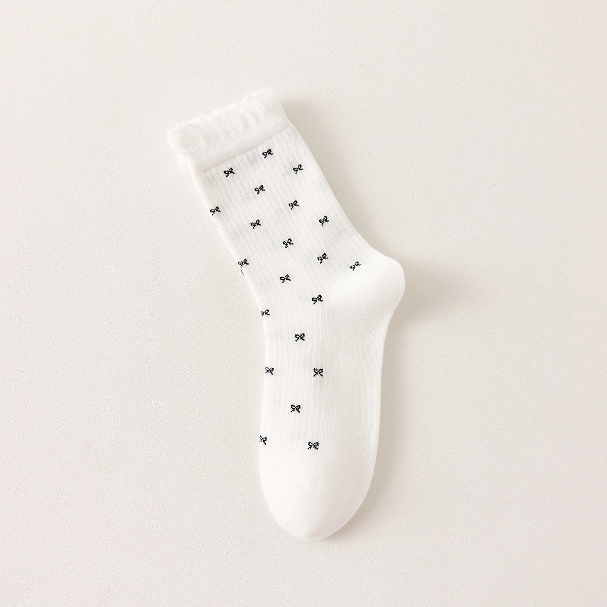 Chaussettes montantes tige côtelée. Motif petit noeud noir. Finition volant sur le haut de tige. Disponibles en blanc, gris chiné clair et noir. 