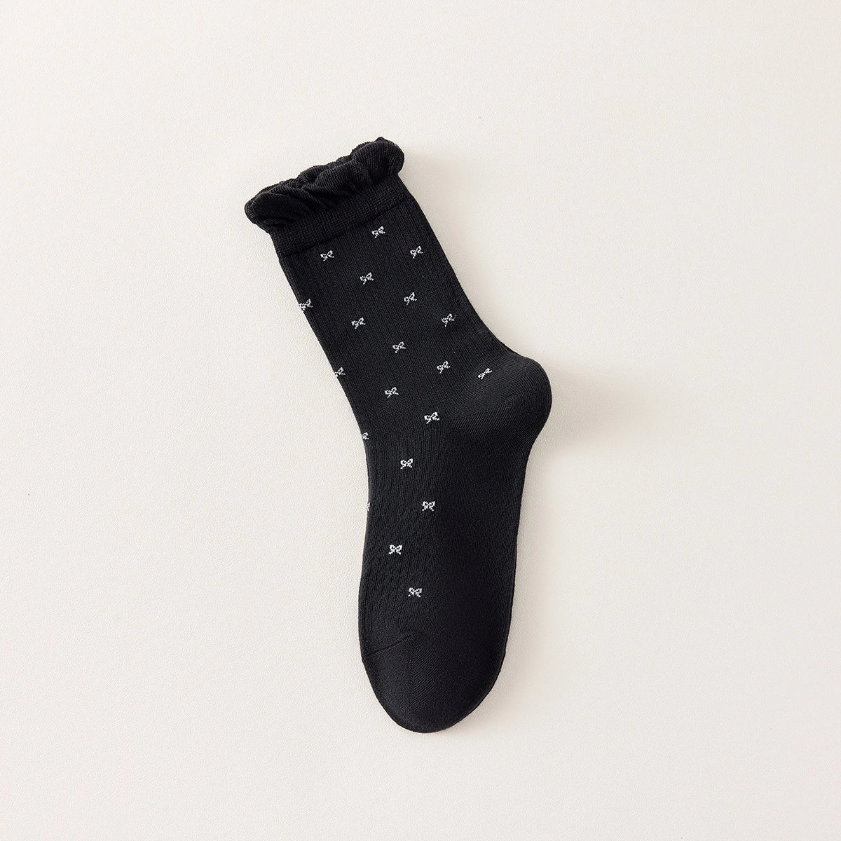 Chaussettes montantes tige côtelée. Motif petit noeud noir. Finition volant sur le haut de tige. Disponibles en blanc, gris chiné clair et noir. 