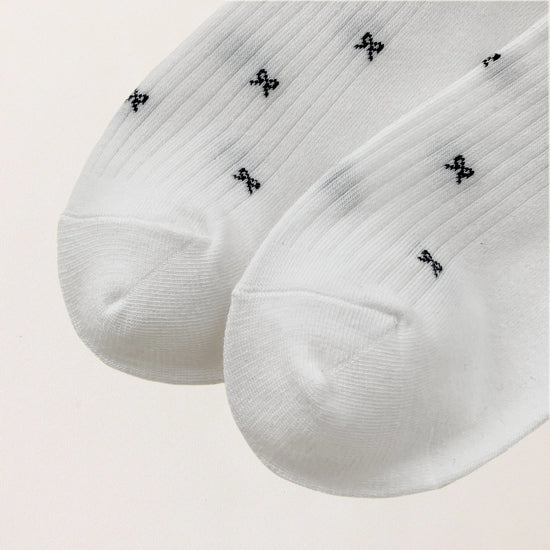 Chaussettes montantes tige côtelée. Motif petit noeud noir. Finition volant sur le haut de tige. Disponibles en blanc, gris chiné clair et noir. 