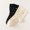 Chaussettes chaudes et douces, effet polaire, motif petits pois, tête d'ours brodée, proposée en noir et blanc cassé.