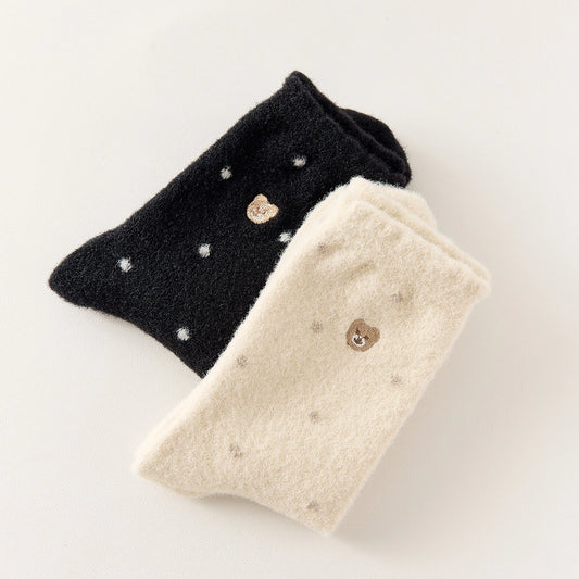 Chaussettes chaudes et douces, effet polaire, motif petits pois, tête d'ours brodée, proposée en noir et blanc cassé.