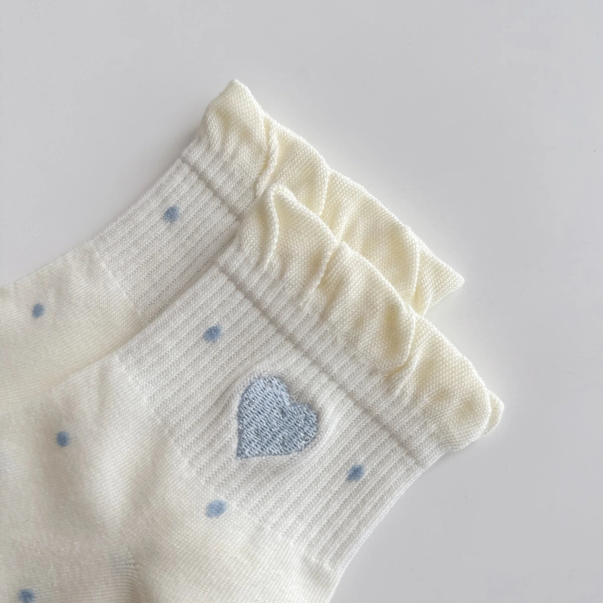 Chaussettes Volant Cœur & Pois femme vendues à l’unité. Modèles blanc à pois bleus ou gris bleu avec volant et cœur brodé. Taille unique 35-41.
