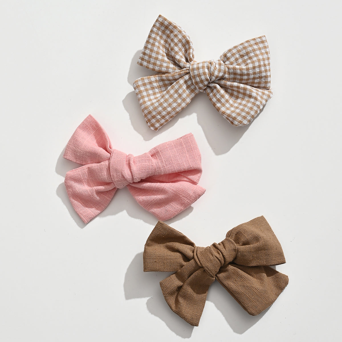 Lot de 3 barrettes pince croco fille avec nœuds en tissu aux tons doux. Accessoires cheveux élégants et confortables pour bébé et enfant.