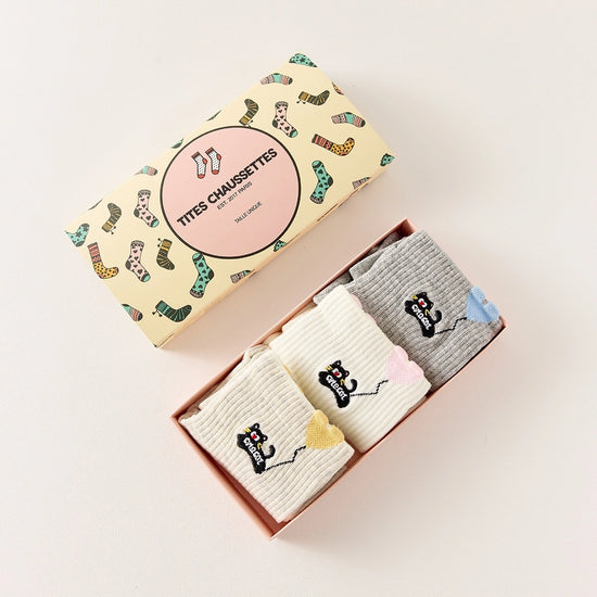 Lot de 3 chaussettes mi-hautes. Motif chat noir tenant un ballon en forme de coeur. Coloris blanc, beige et gris. Coeur contrasté.