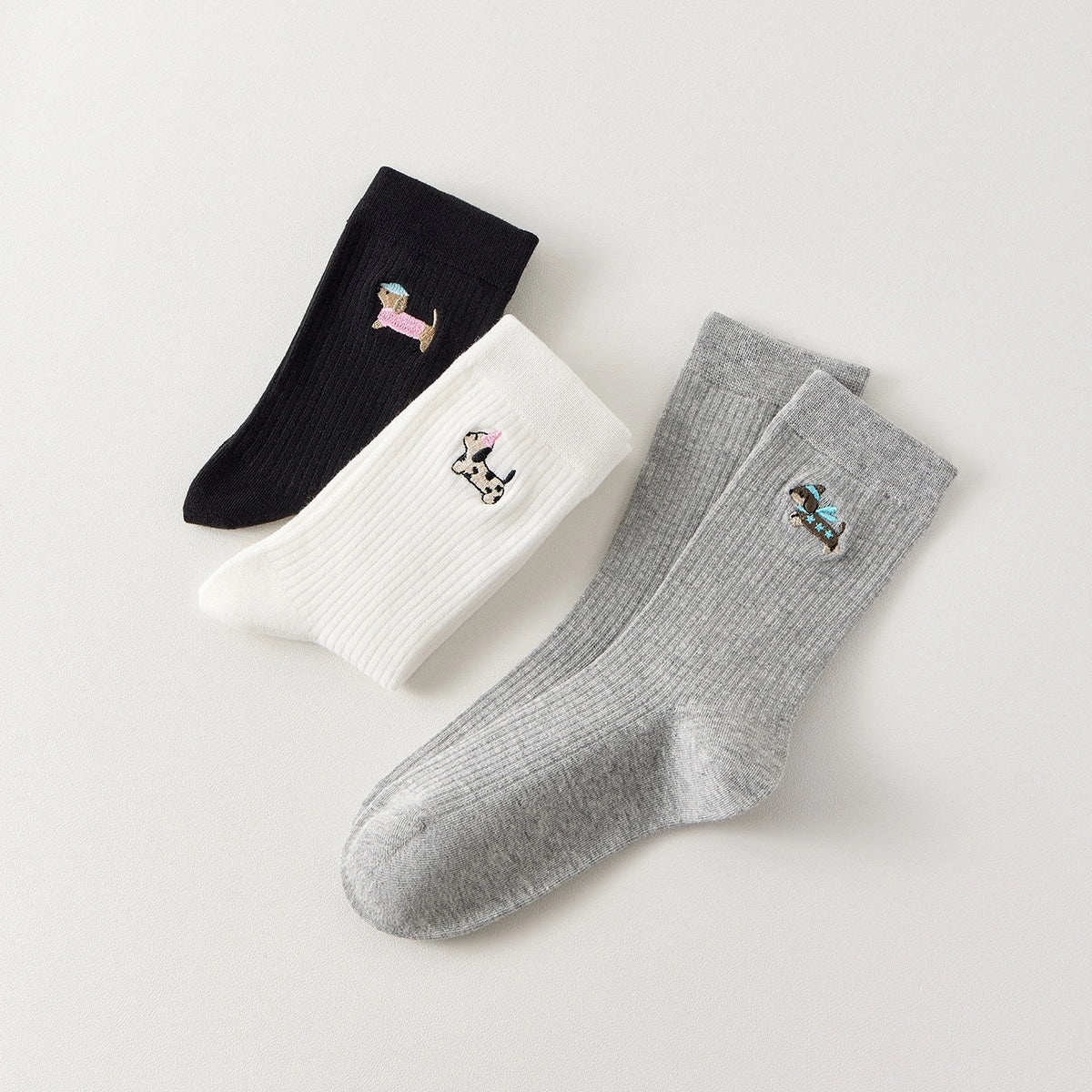 Lot de 3 chaussettes hautes côtelées. Coloris noir, gris chiné, blanc. Broderie petit chien sur l'extérieur du pied. 
