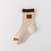 Lot de 5 chaussettes pour enfant (garçon).  Coloris beige / marron clair / marron foncé. Graphisme inspirés de l’univers citadin : inscription taxi, rayures, pois, numéro. 