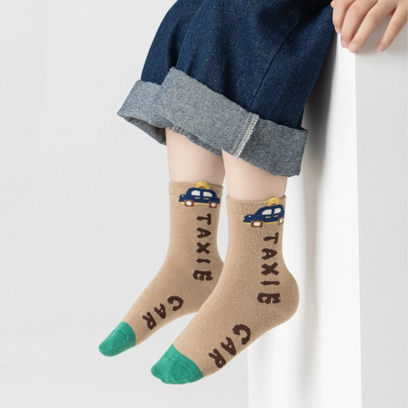 Lot de 5 chaussettes pour enfant (garçon).  Coloris beige / marron clair / marron foncé. Graphisme inspirés de l’univers citadin : inscription taxi, rayures, pois, numéro. 