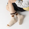 Lot de 5 chaussettes pour enfant (garçon).  Coloris beige / marron clair / marron foncé. Graphisme inspirés de l’univers citadin : inscription taxi, rayures, pois, numéro. 