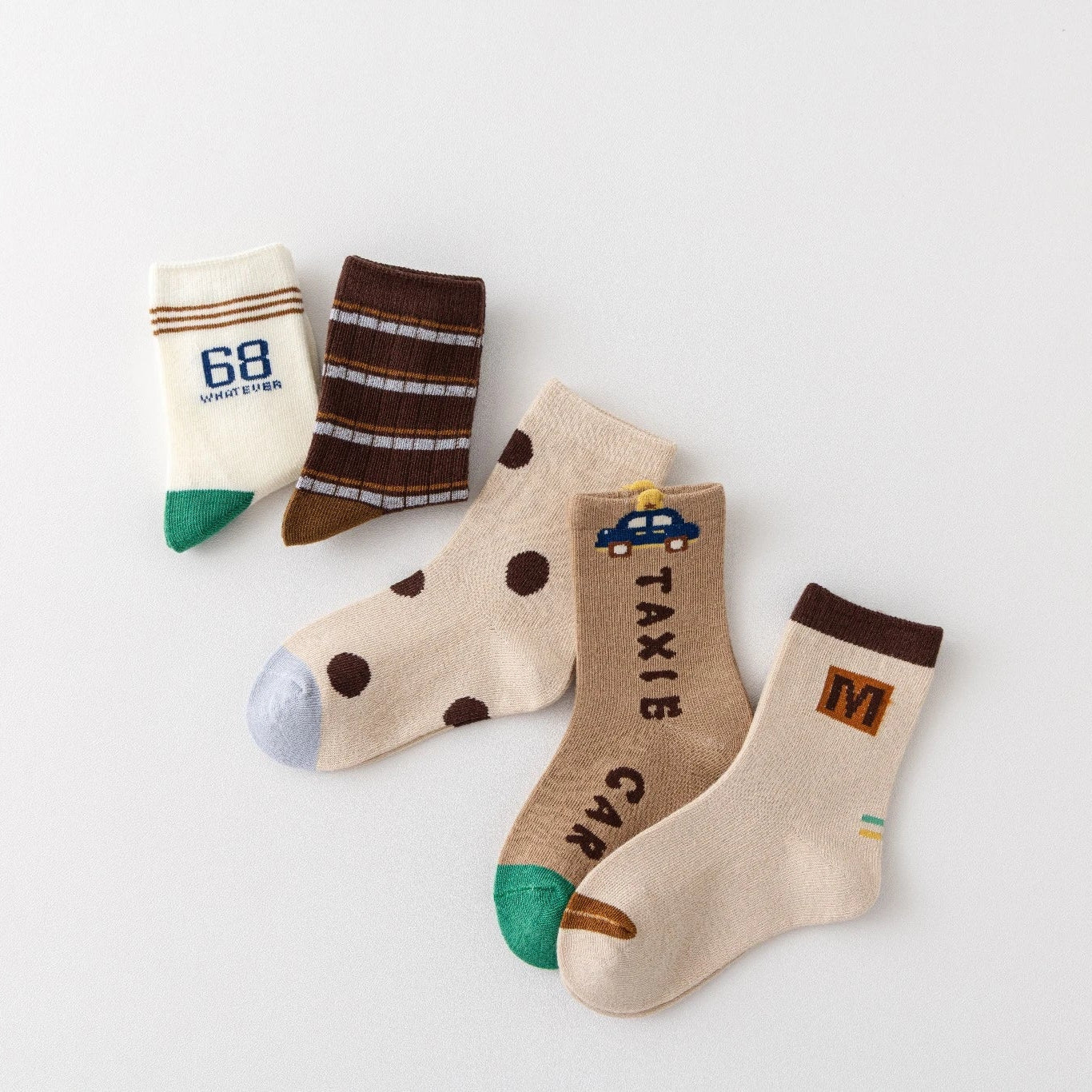 Lot de 5 chaussettes pour enfant (garçon).  Coloris beige / marron clair / marron foncé. Graphisme inspirés de l’univers citadin : inscription taxi, rayures, pois, numéro. 