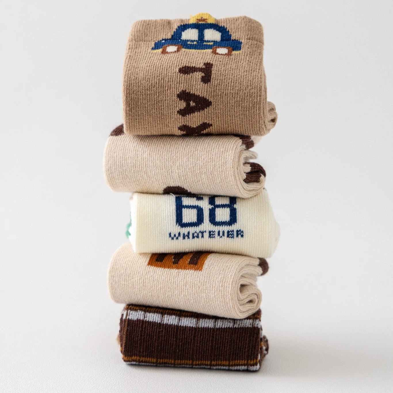 Lot de 5 chaussettes pour enfant (garçon).  Coloris beige / marron clair / marron foncé. Graphisme inspirés de l’univers citadin : inscription taxi, rayures, pois, numéro. 