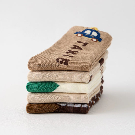 Lot de 5 chaussettes pour enfant (garçon).  Coloris beige / marron clair / marron foncé. Graphisme inspirés de l’univers citadin : inscription taxi, rayures, pois, numéro. 