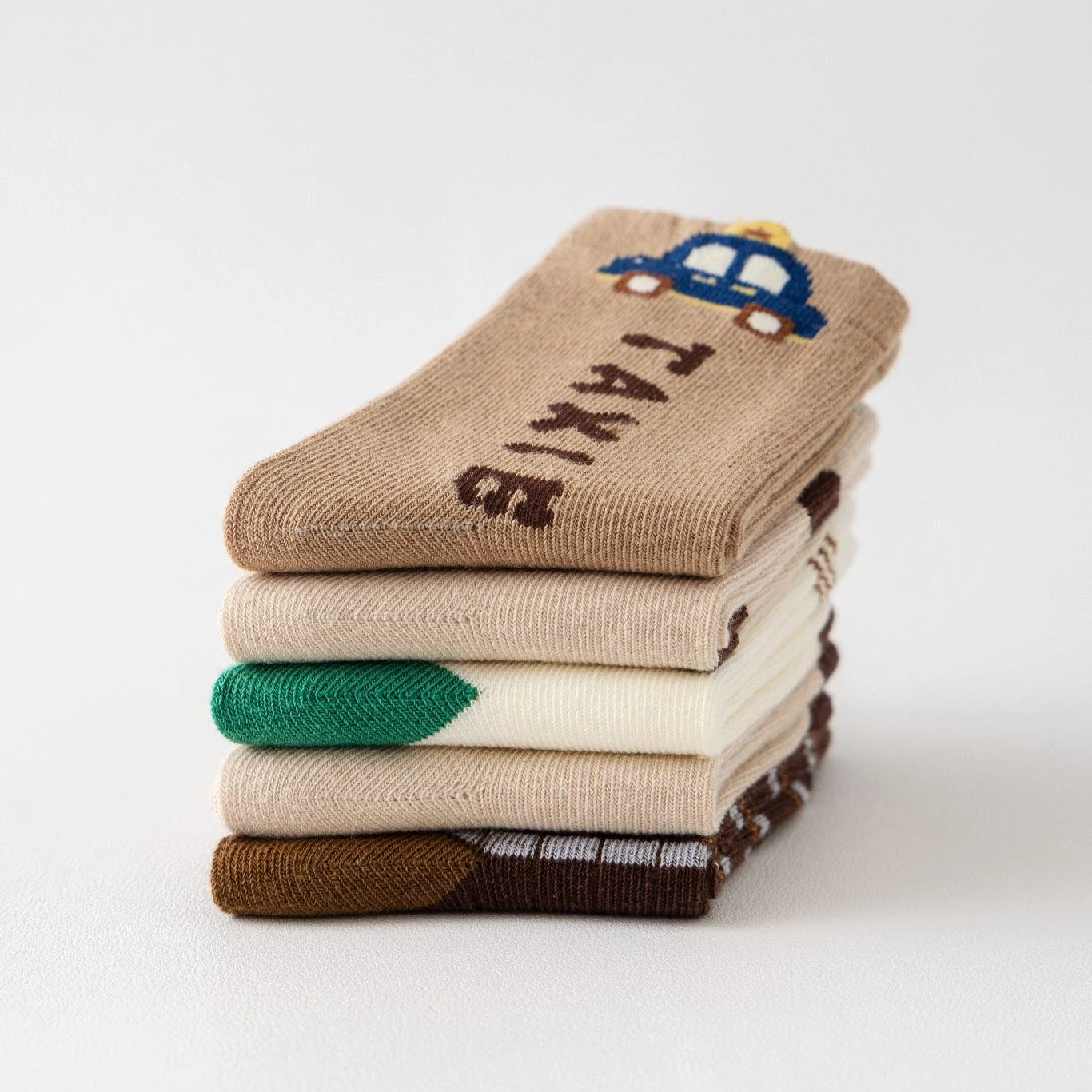 Lot de 5 chaussettes pour enfant (garçon).  Coloris beige / marron clair / marron foncé. Graphisme inspirés de l’univers citadin : inscription taxi, rayures, pois, numéro. 