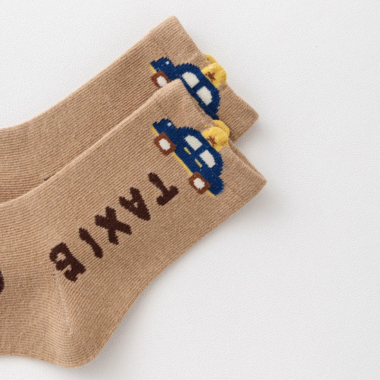 Lot de 5 chaussettes pour enfant (garçon).  Coloris beige / marron clair / marron foncé. Graphisme inspirés de l’univers citadin : inscription taxi, rayures, pois, numéro. 