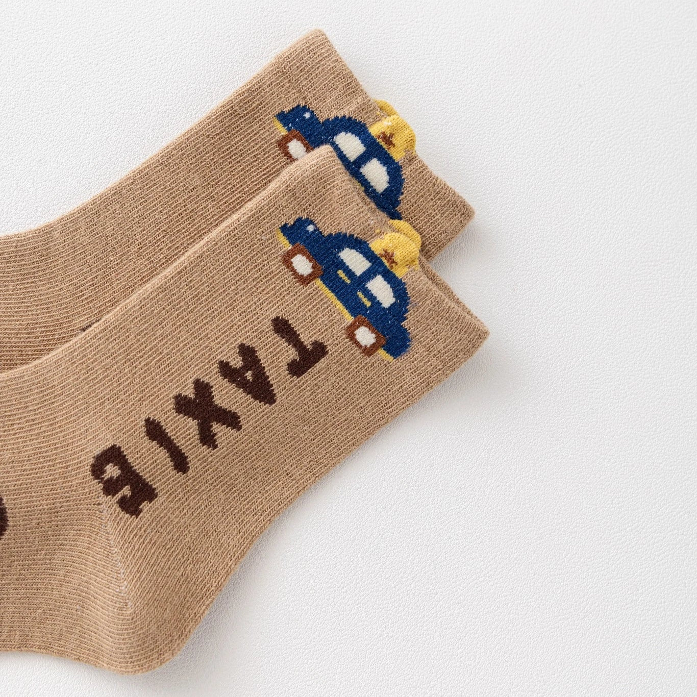 Lot de 5 chaussettes pour enfant (garçon).  Coloris beige / marron clair / marron foncé. Graphisme inspirés de l’univers citadin : inscription taxi, rayures, pois, numéro. 